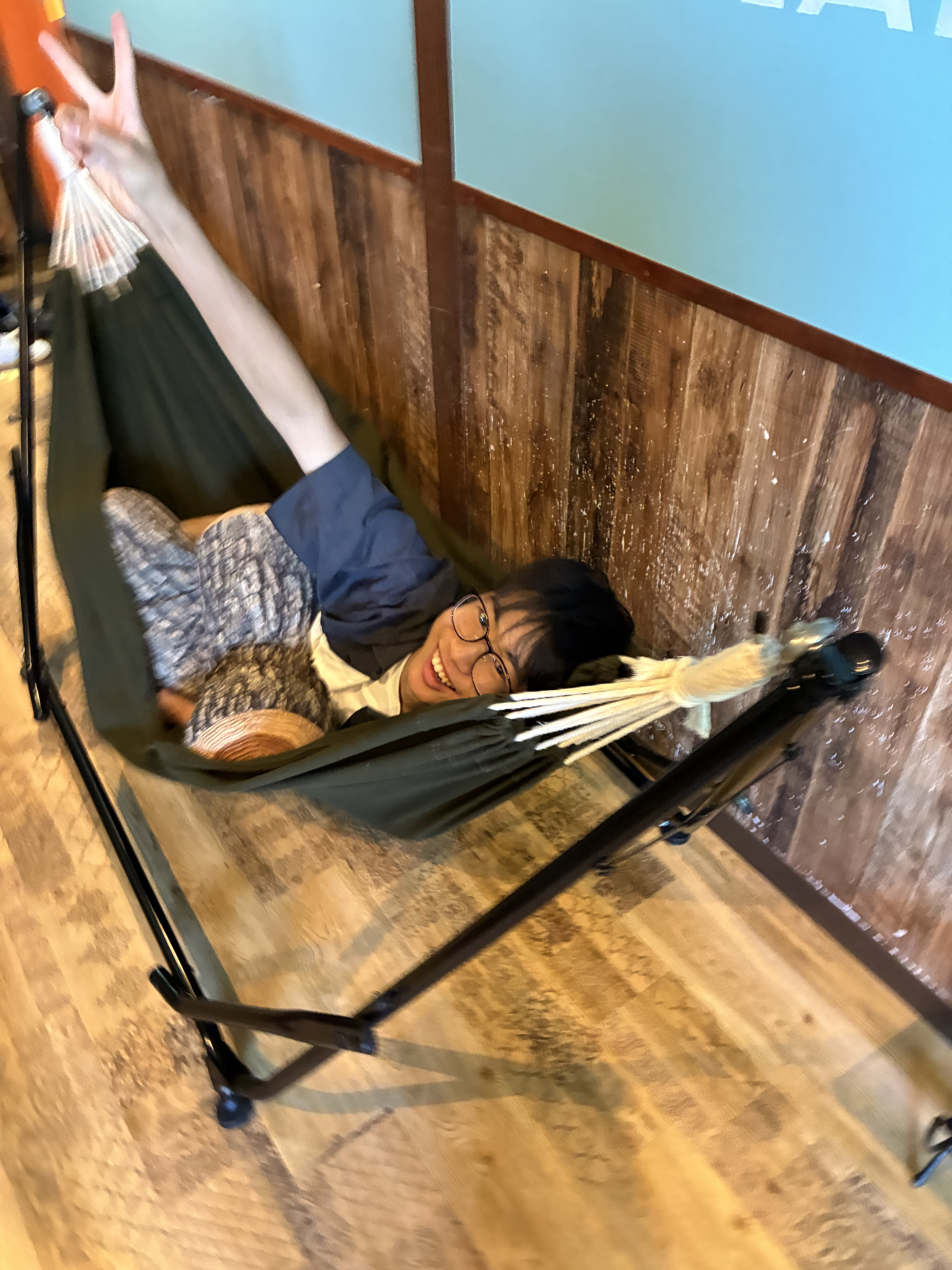 宿泊室のハンモックに寝転んでピースサインをする生徒