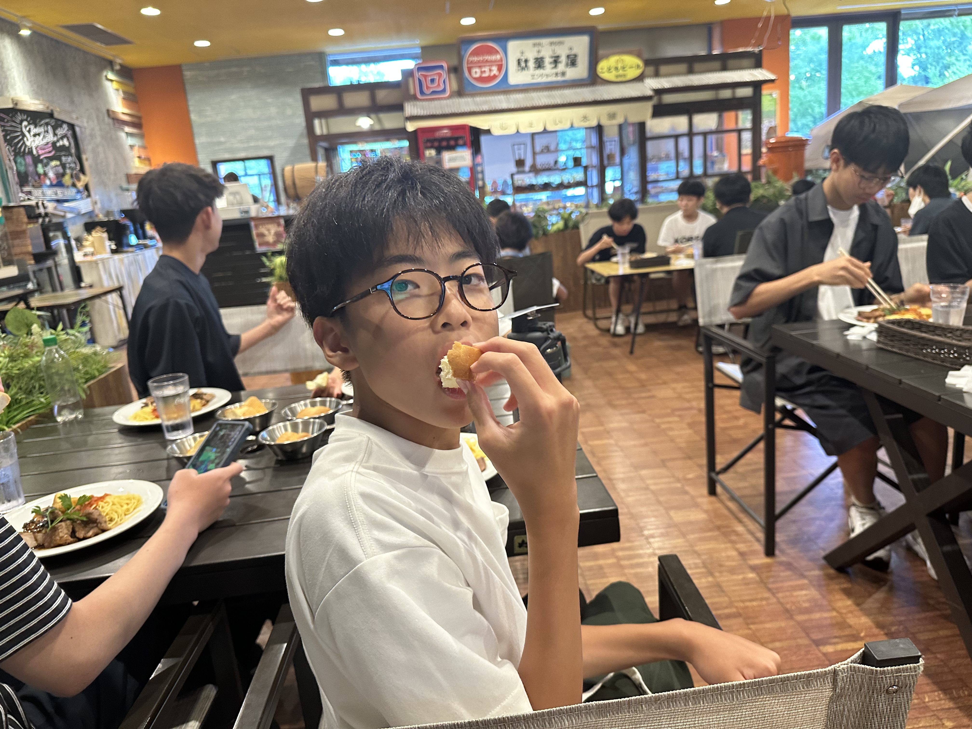 ロゴスランドの食事会場で、揚げたての料理を頬張る生徒