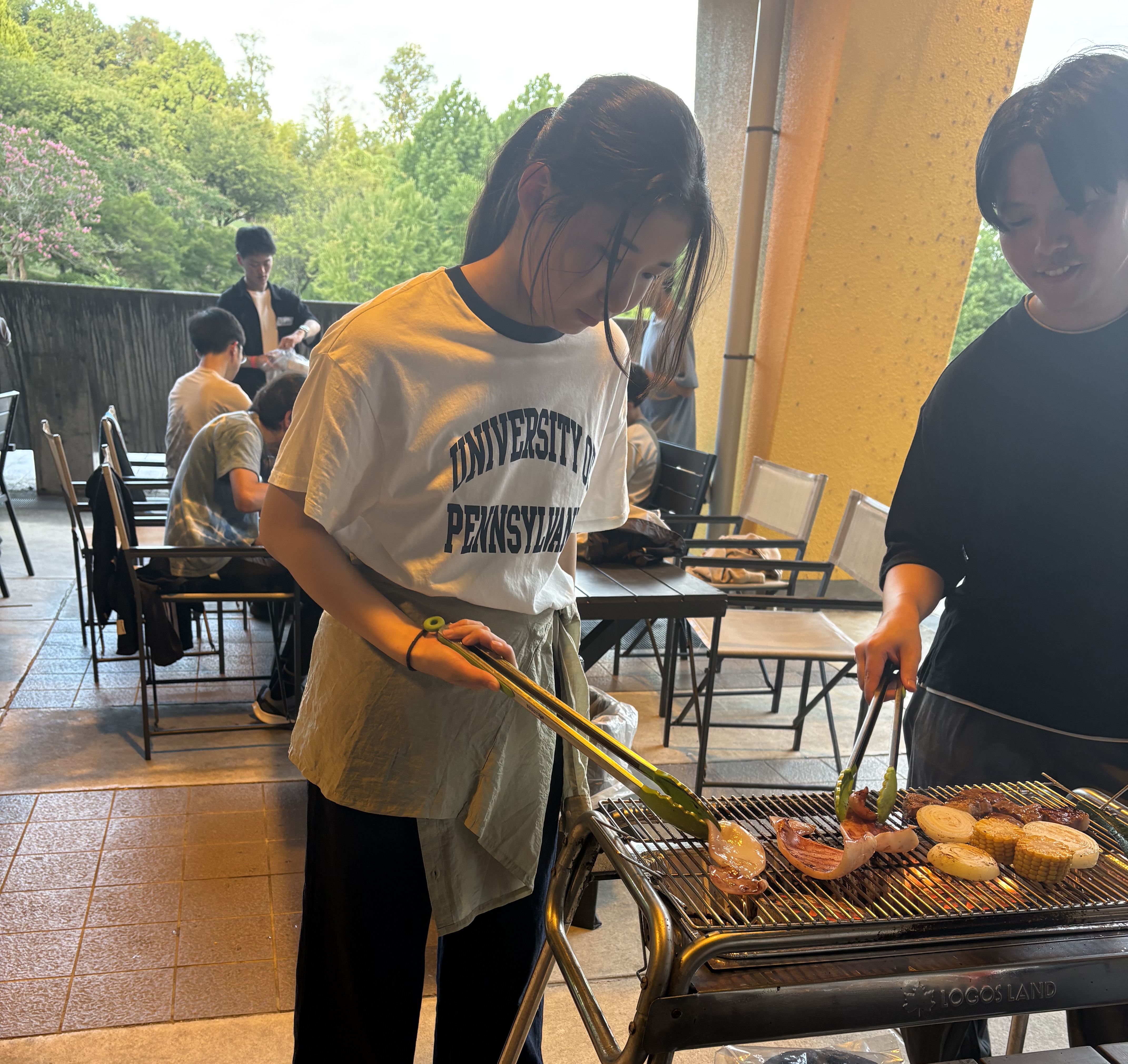 BBQのコンロでトングを使い、肉や野菜を焼くスタッフ