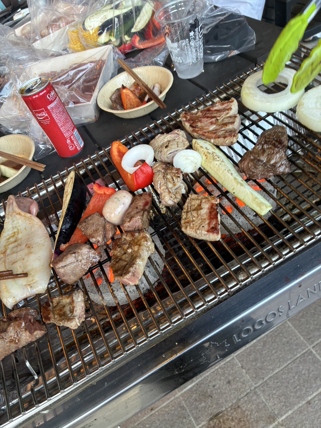 BBQの網の上で焼かれる肉やイカ、玉ねぎ・パプリカなどの野菜